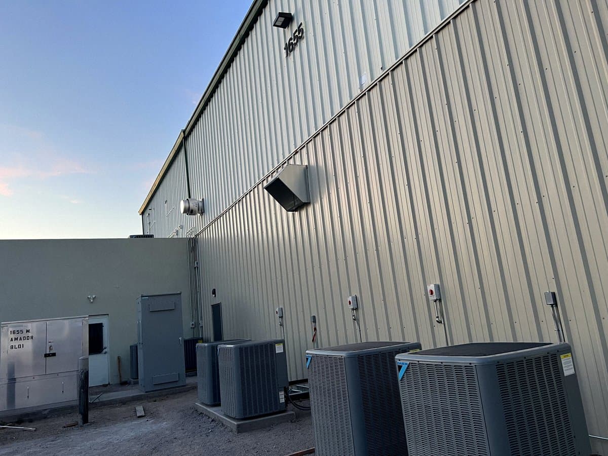 Condensing units on a concrete pad beside a metal warehouse