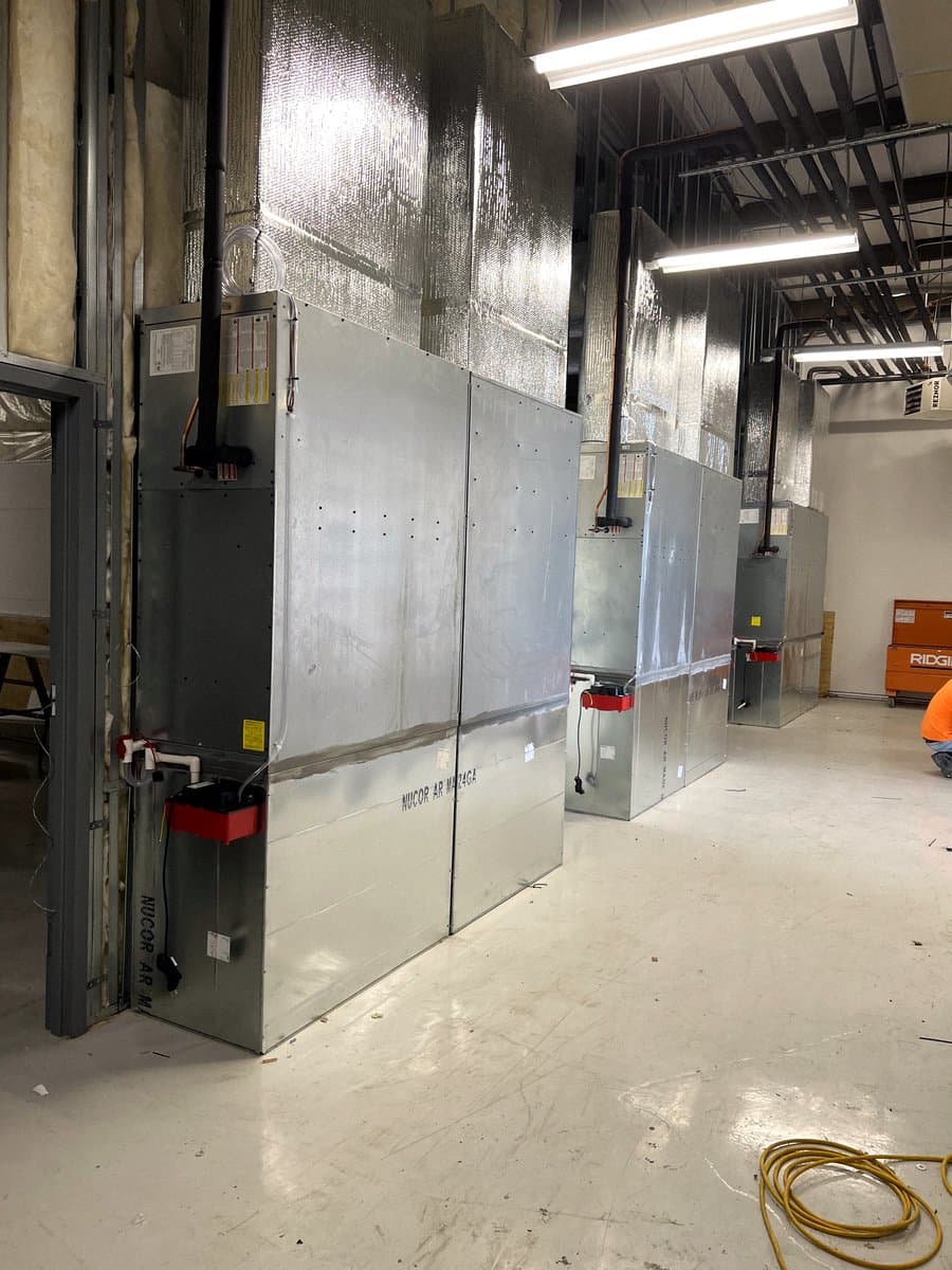 Row of vertical air handlers and sheet-metal plenums in a mechanical room